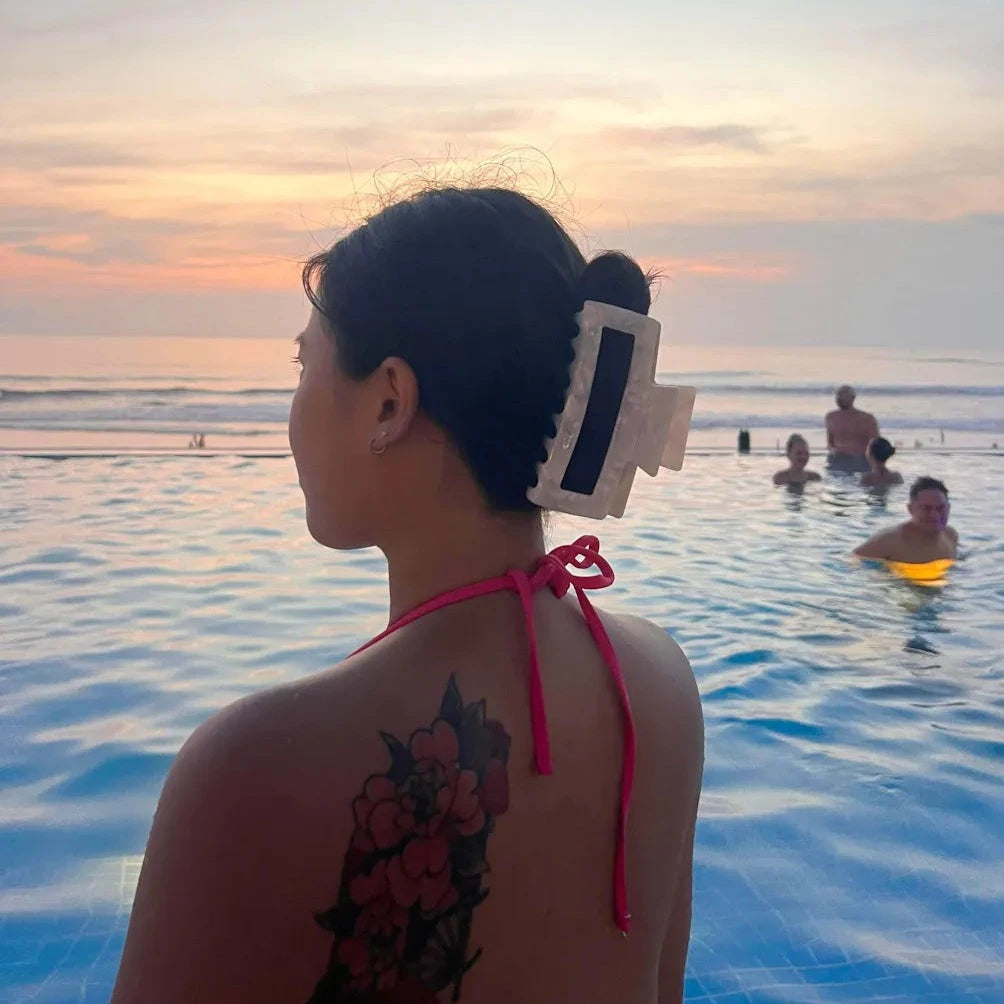claw clip in a pearl colour worn by woman in red bikini in the swimming pool overlooking a sunset