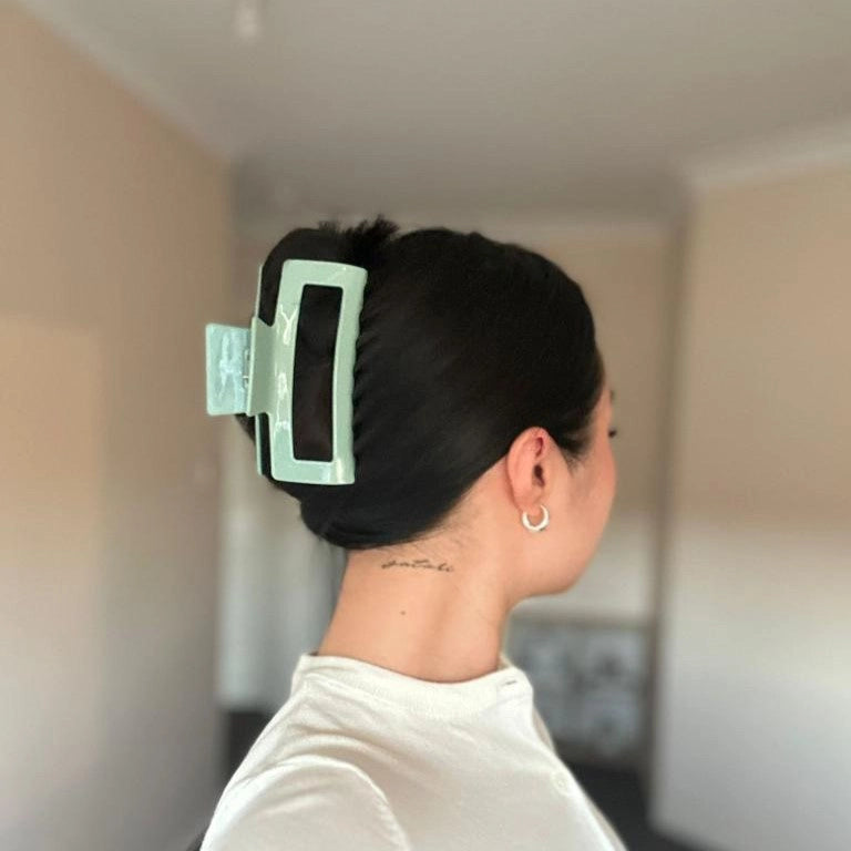 woman with black hair wearing a green large claw clip