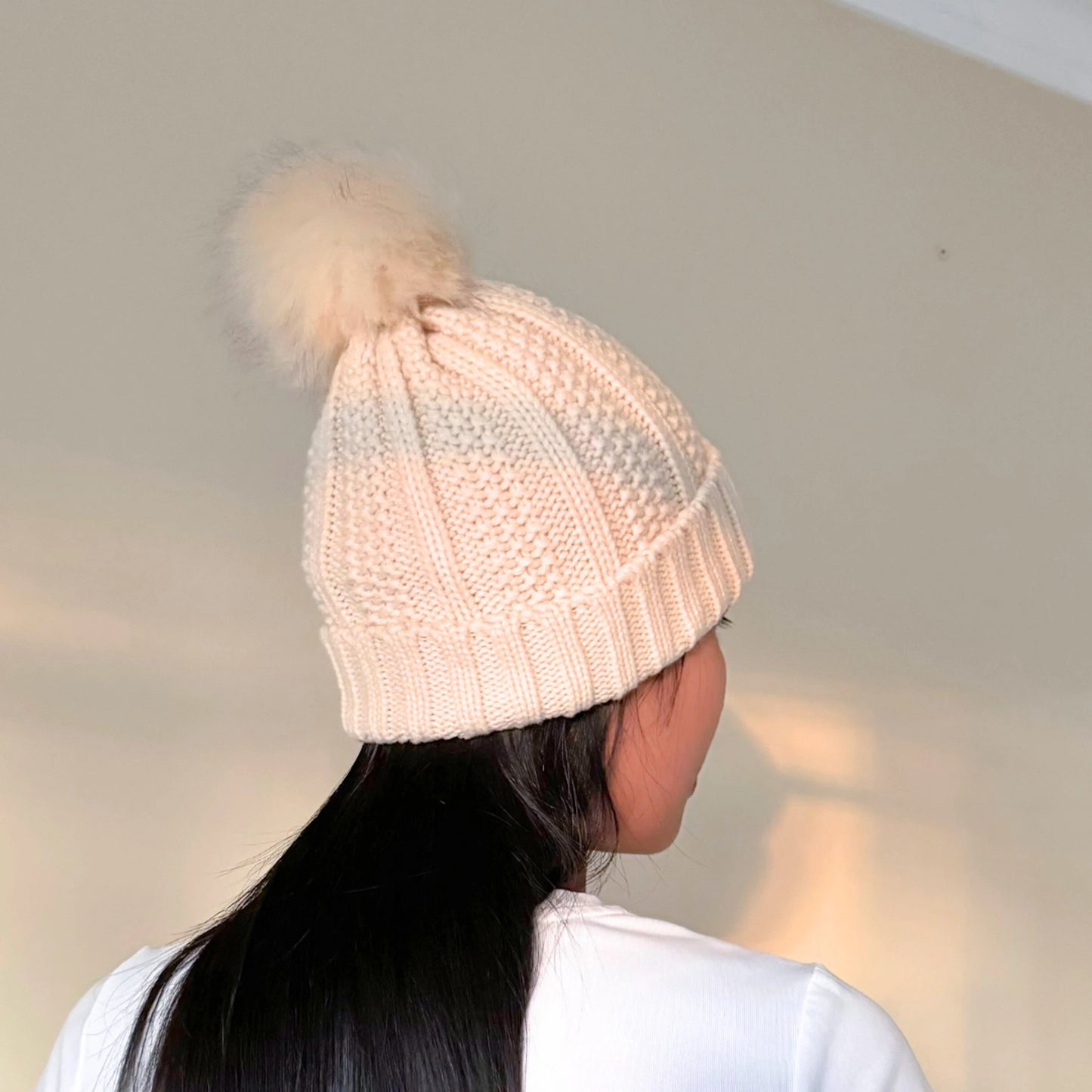 girl with black hair wearing a beige beanie with satin lining in front of a cream background