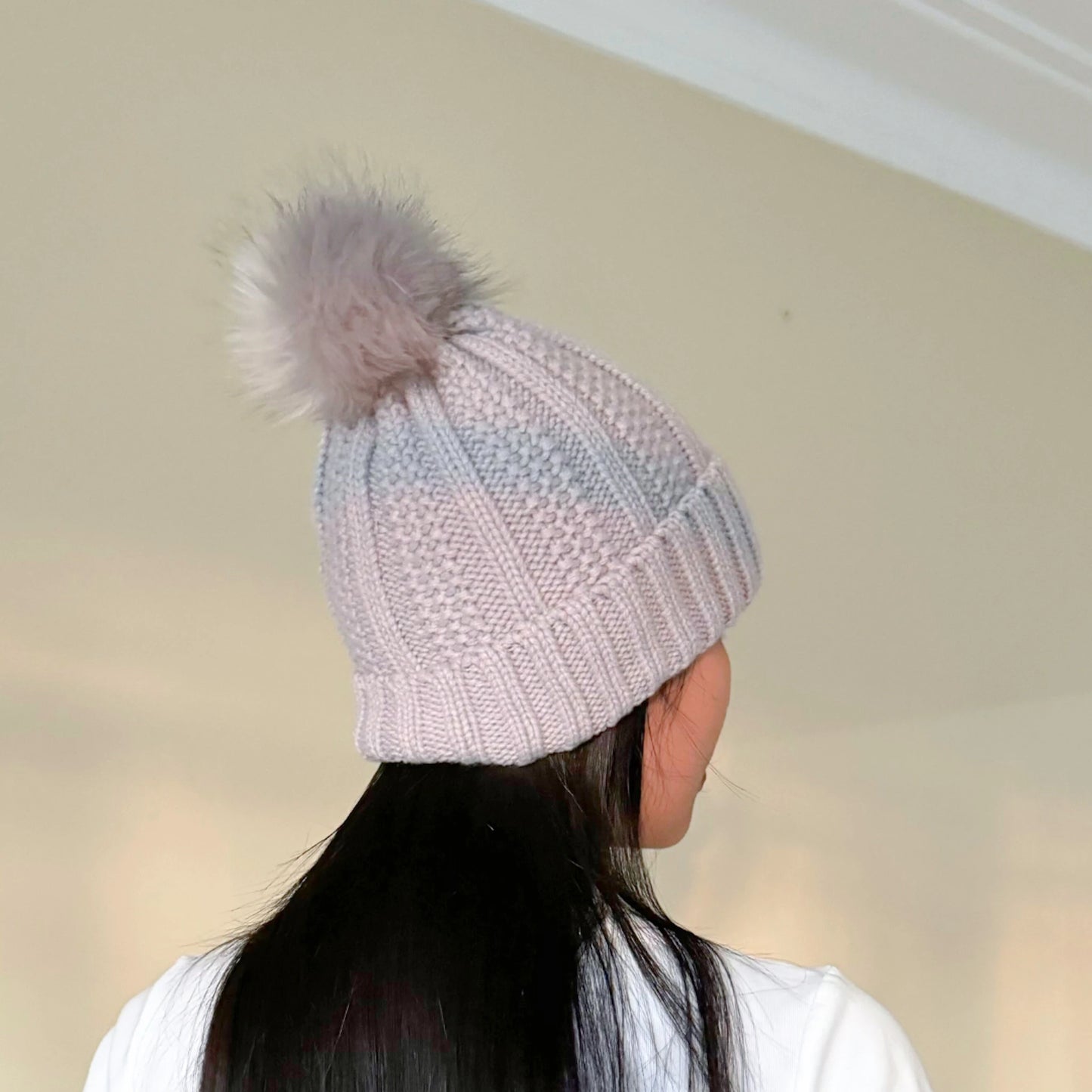 girl with black hair wearing a grey beanie with satin lining in front of a cream background