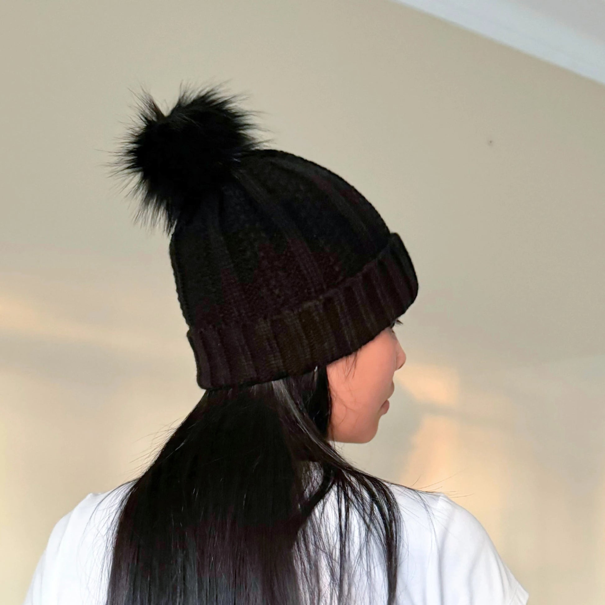 girl with black hair wearing a black beanie with satin lining in front of a cream background