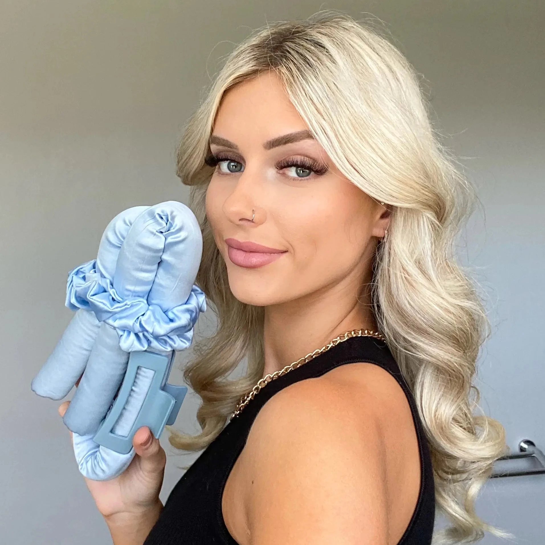 Woman with blonde curled hair holding heatless curler in blue