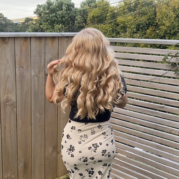 woman with long blonde curled hair using a heatless curler