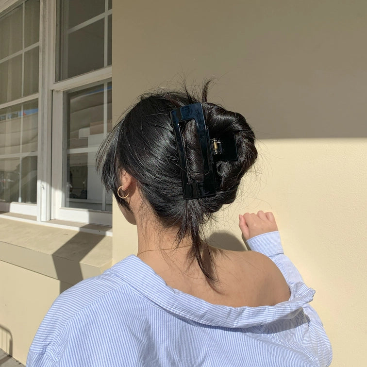 woman with black hair wearing a black claw clip and a blue and white stripped shirt