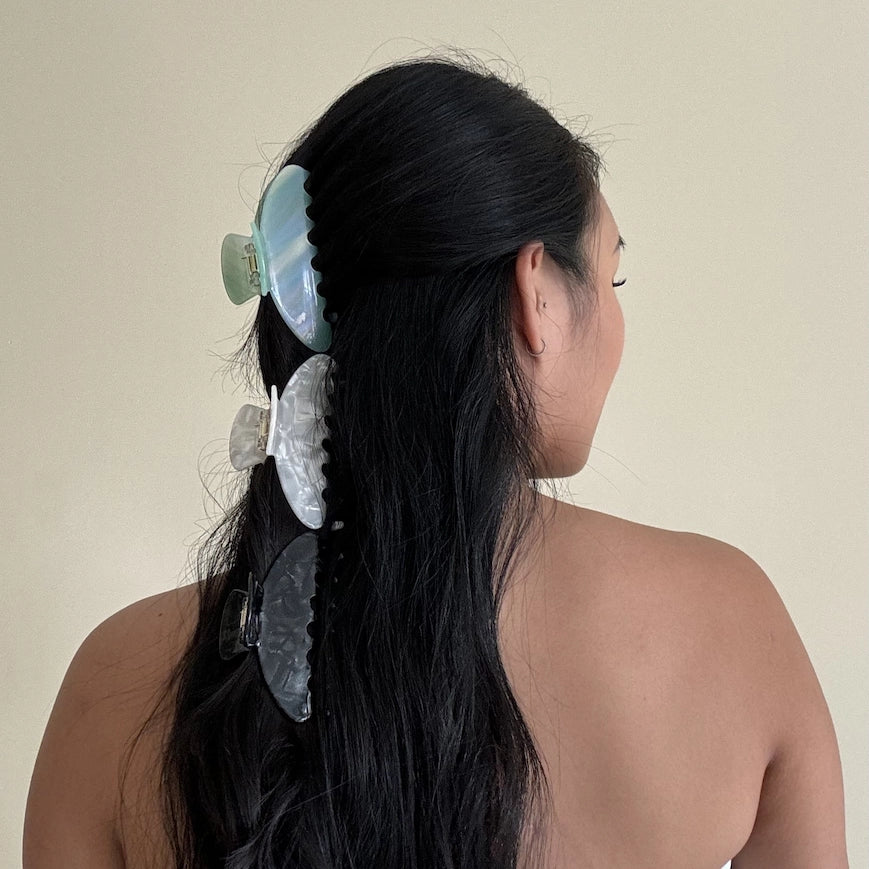 woman with black hair wearing large claw clips with crescent design in a green jade oyster and black onyx colour 